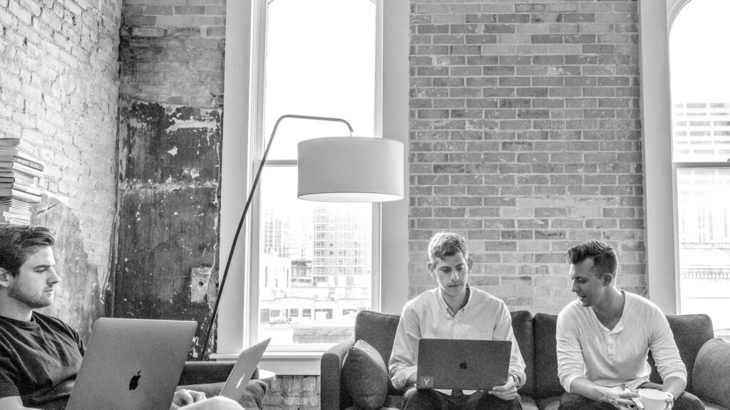 Marketing team working together with laptops in a bright office, shown in monochrome.