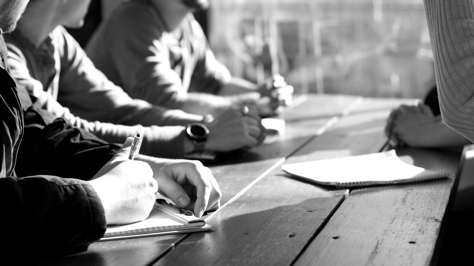People sitting on chair in front of table while holding pens during daytime.