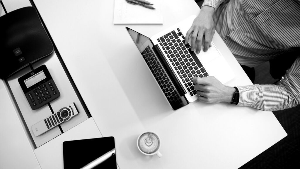 Person using laptop on white wooden table.