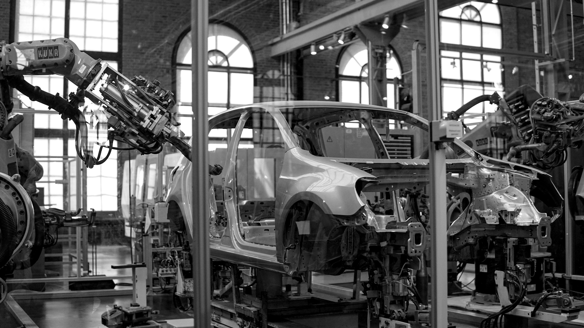 Gray vehicle being fixed inside factory using robot machines.
