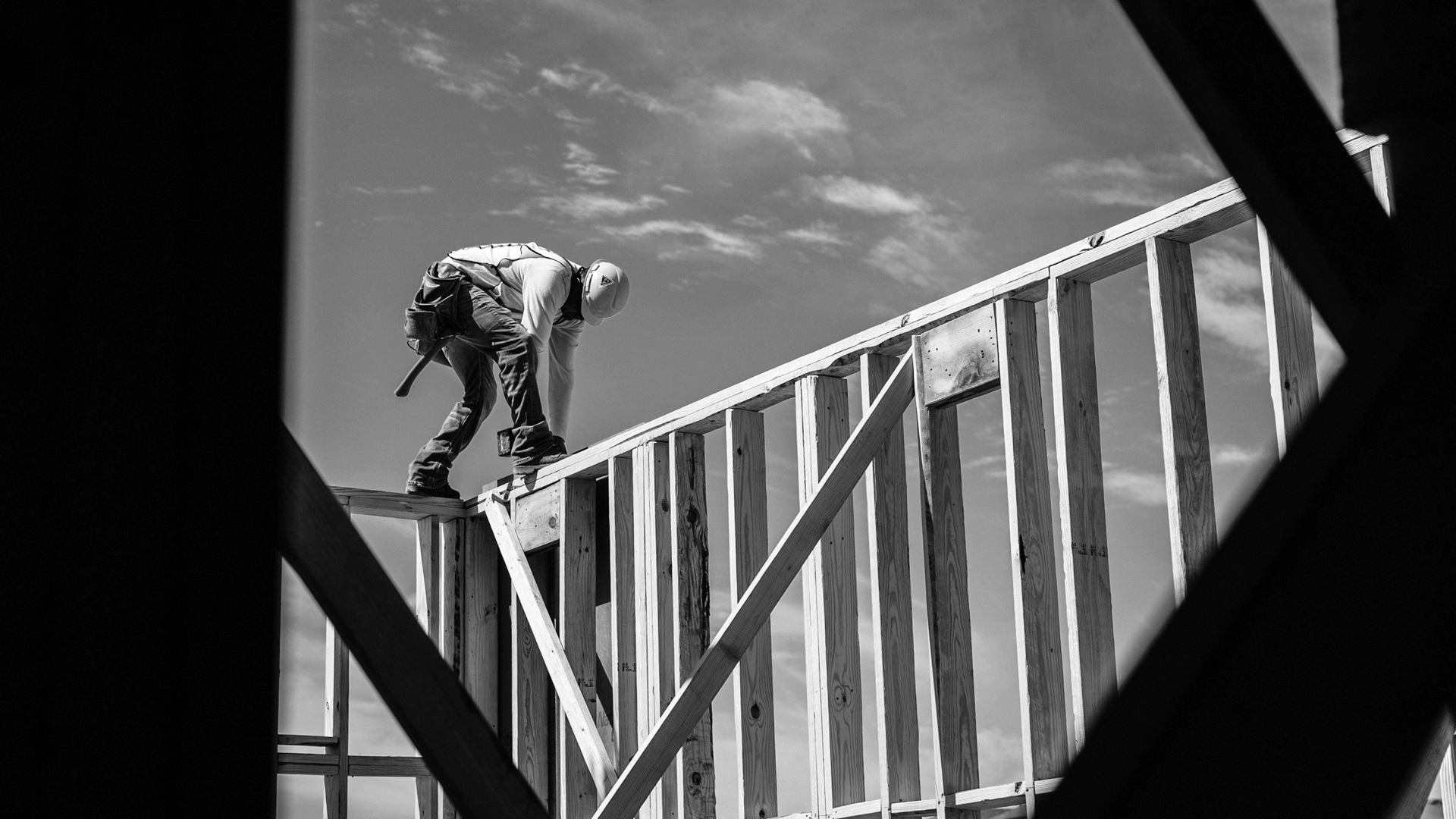 Construction worker in hard hat on building frame.