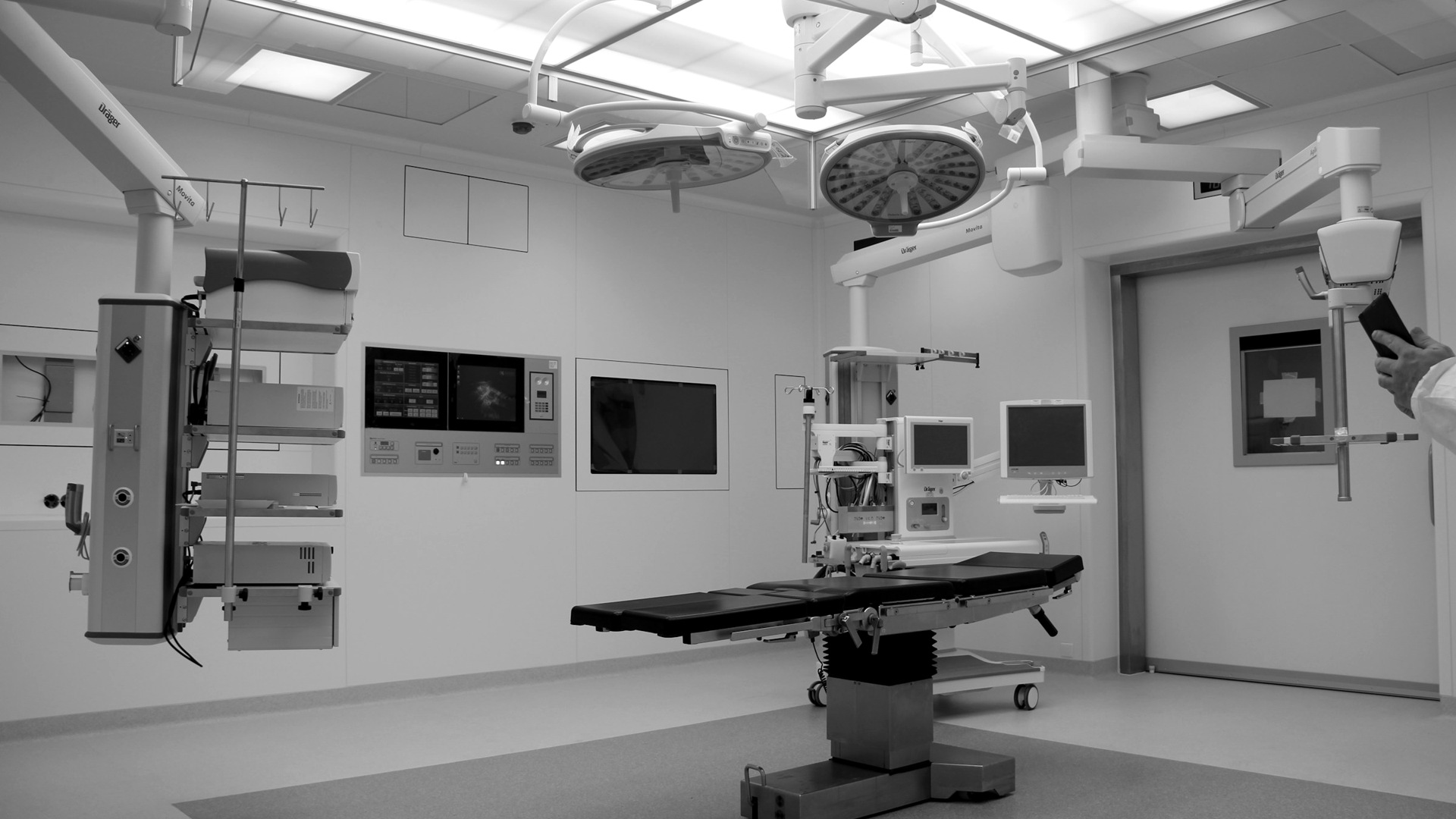 An operating room with a surgical table, overhead lights, and medical equipment.