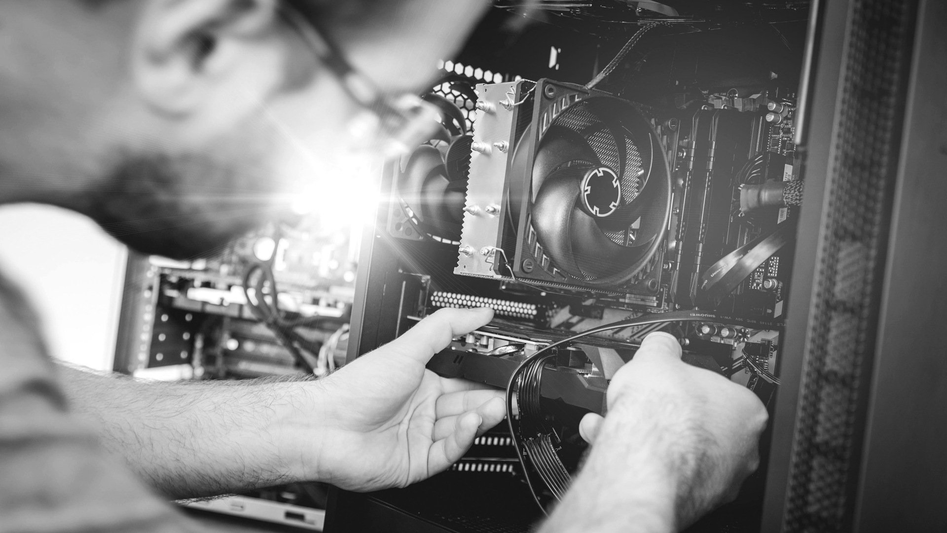 A person installing a graphics card into a computer case with a cooling fan.