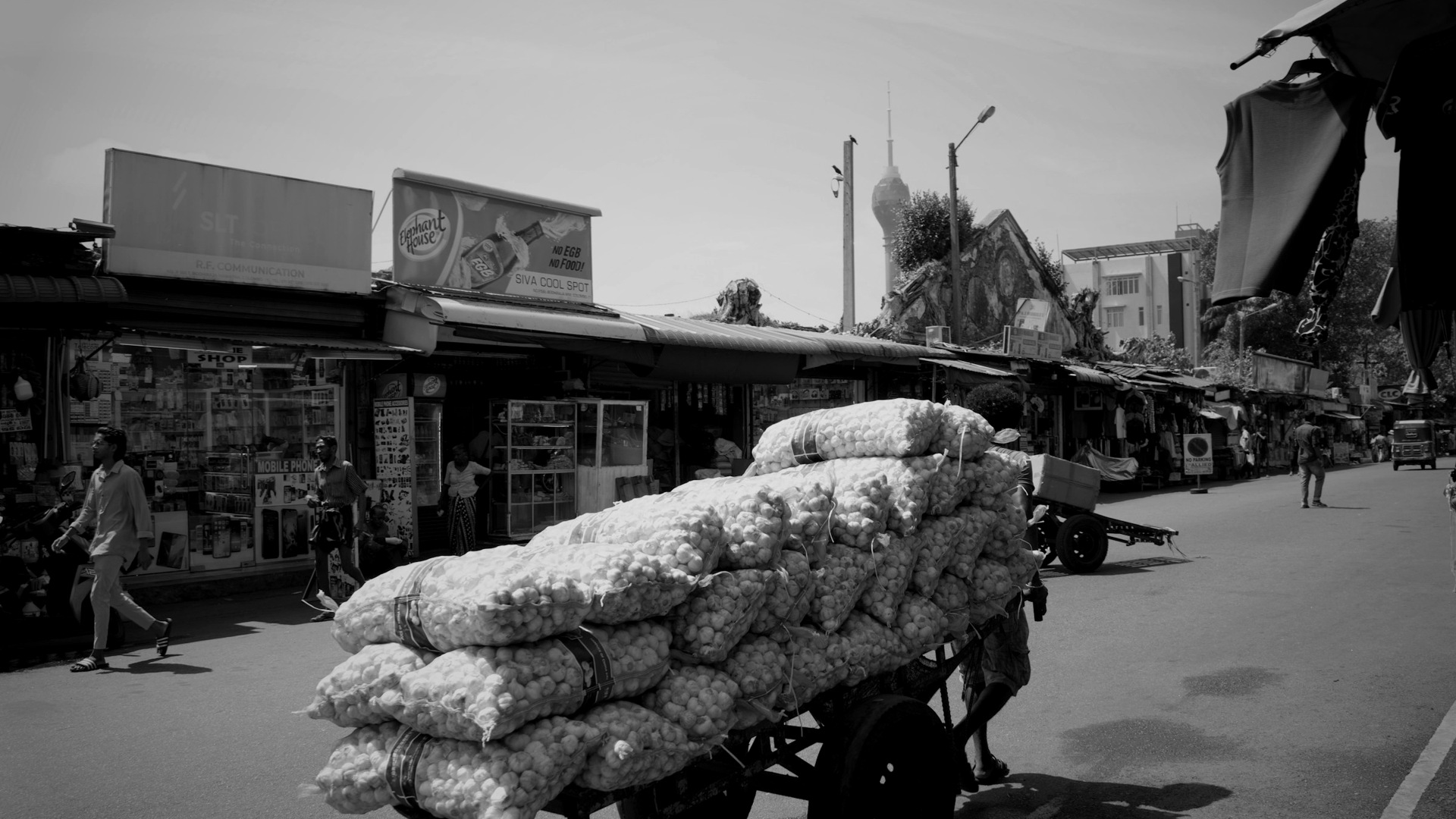 Cart loaded with sacks of produce on a street.