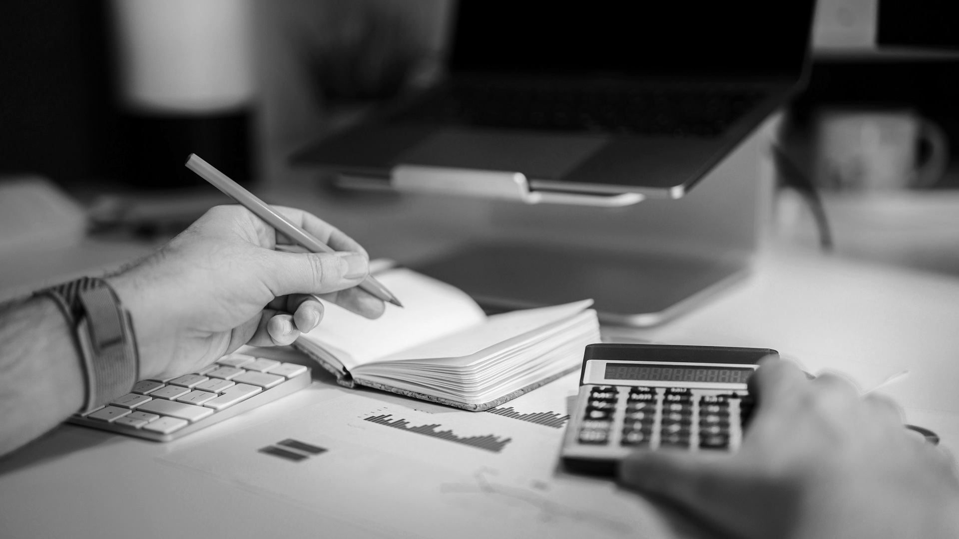 A person sitting at a desk with a calculator and a notebook.