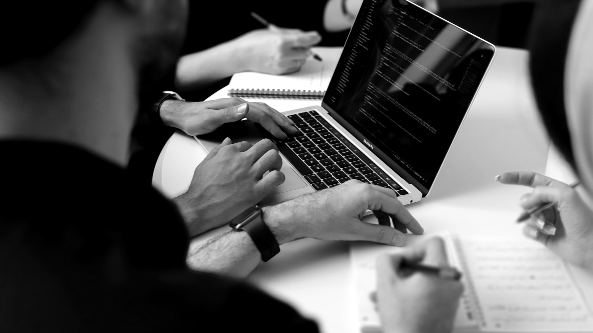 A group of people sitting around a laptop computer.