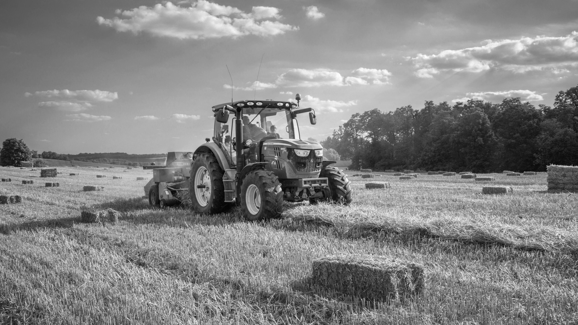 Green tractor on brown grass field under blue sky during daytime.