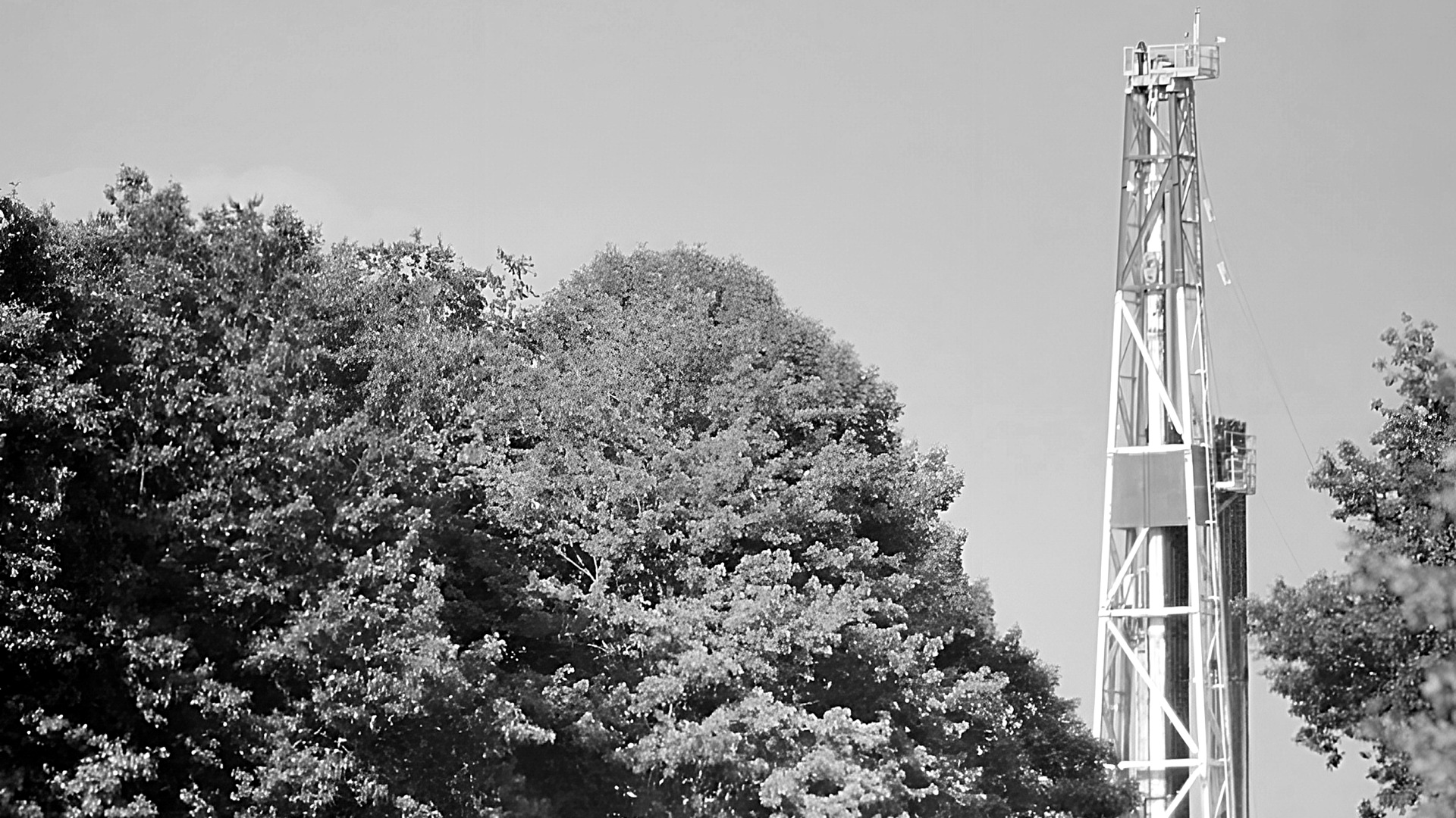 A blue and white drilling rig next to trees.