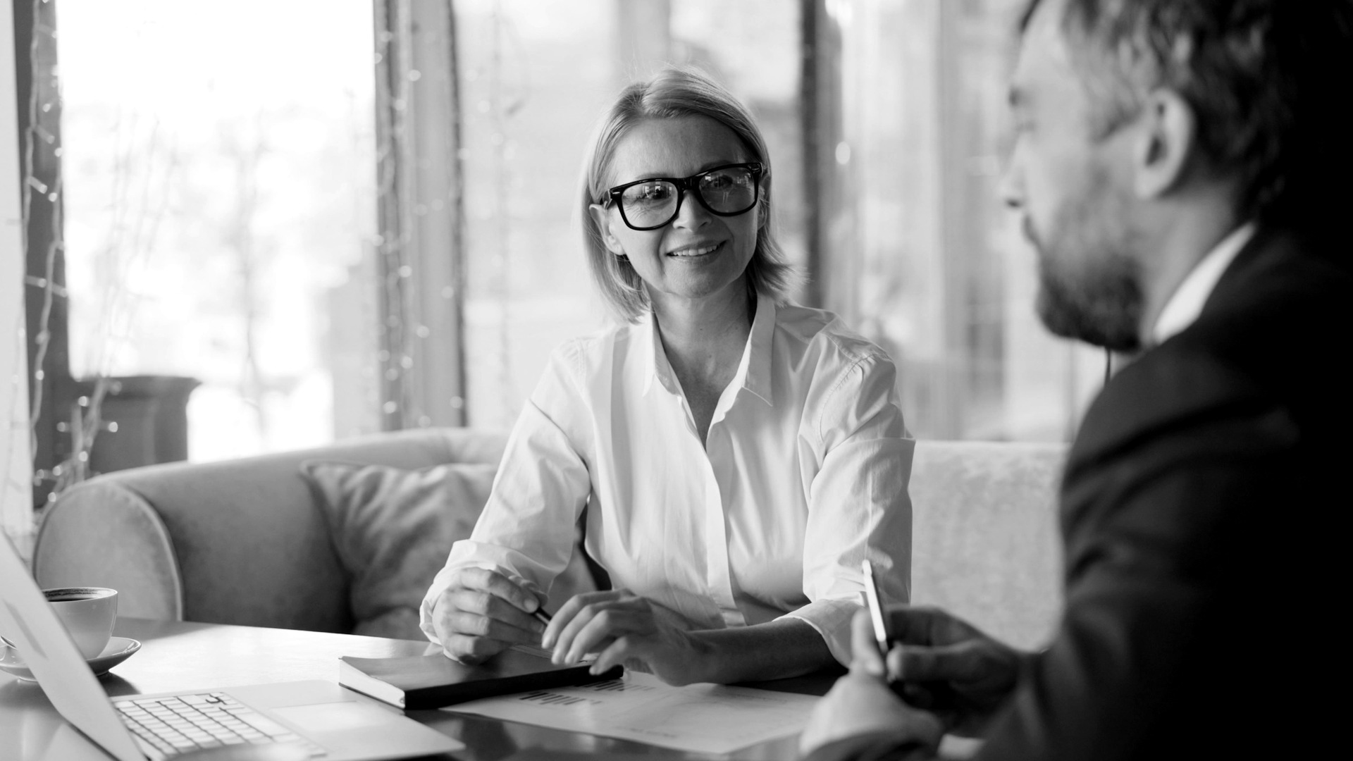 A man and woman sitting at a table with a laptop.