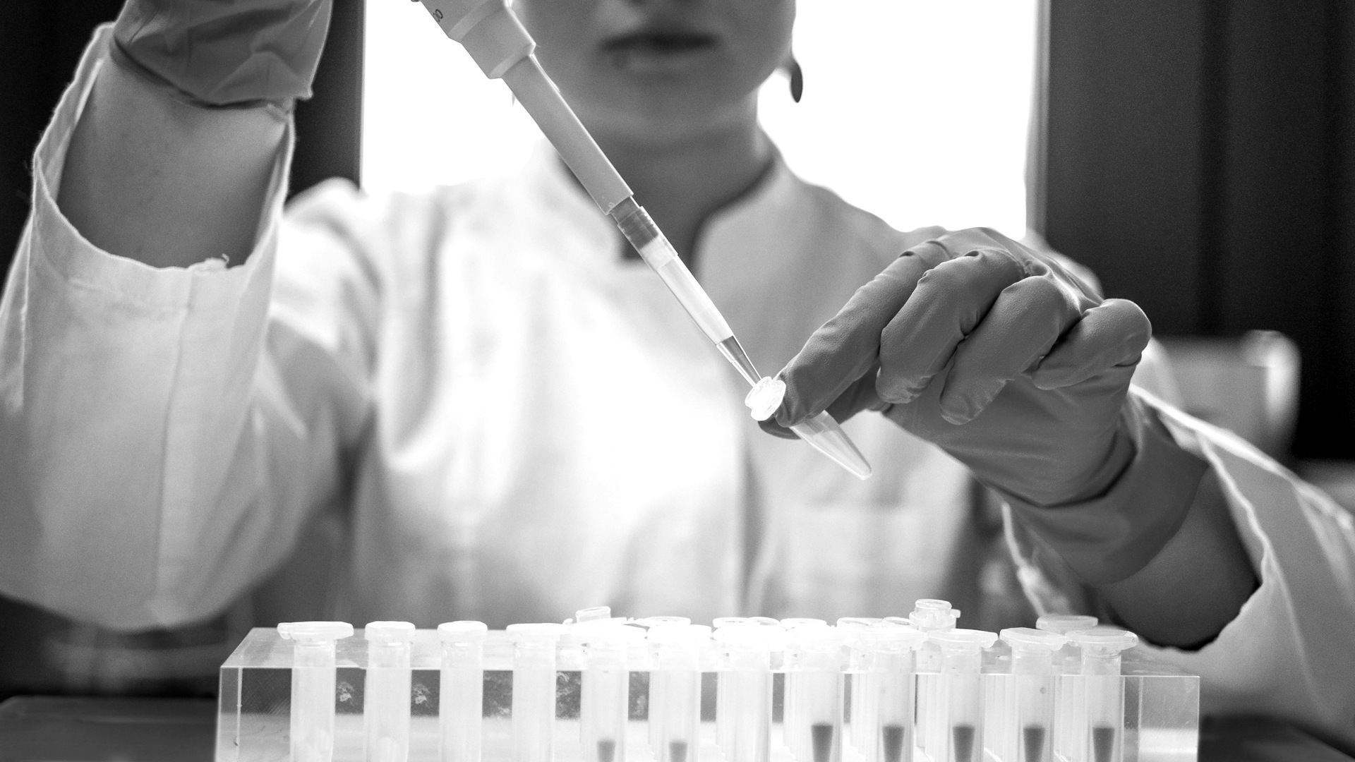 Scientist using pipette with test tubes in lab.