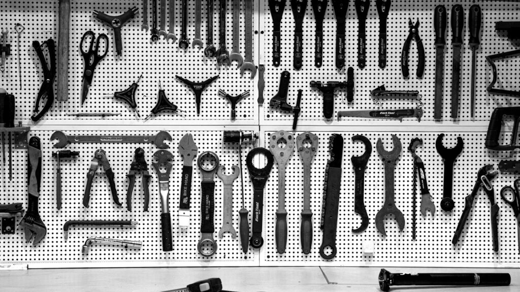 A bunch of tools hanging up on a wall.